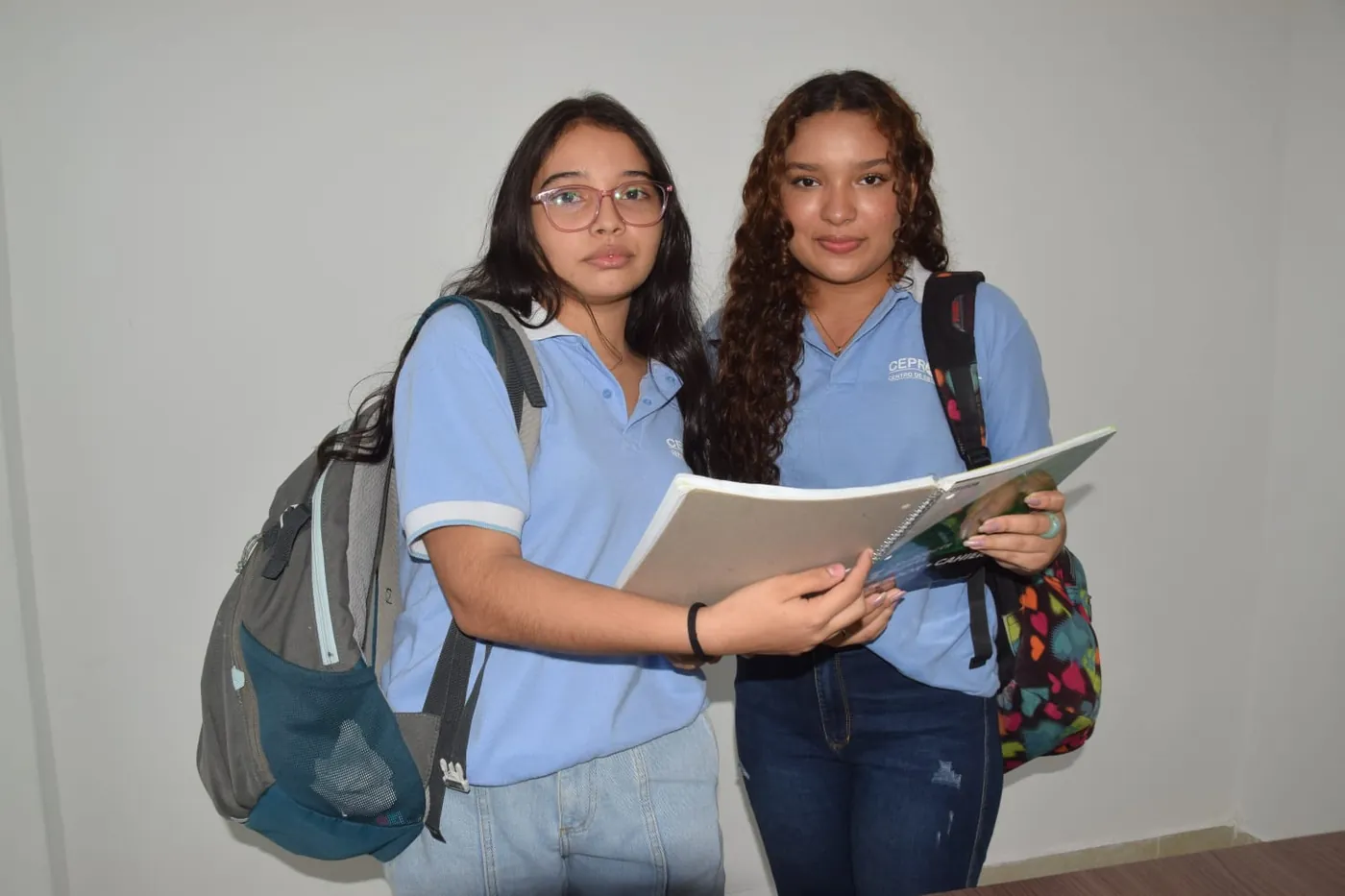 Dos estudiantes de CEPRODENT repasan juntas un cuaderno con el uniforme institucional